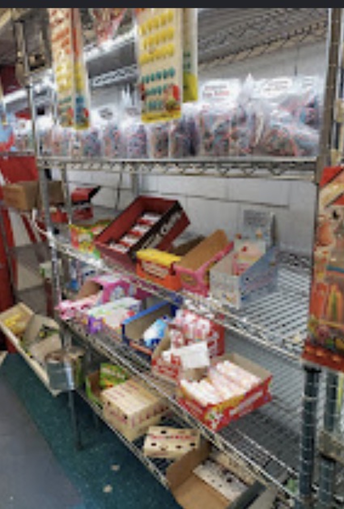 Metal shelves stacked with boxed candy and hanging bags in the candy aisle